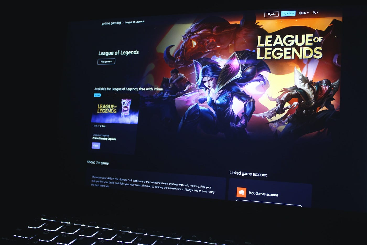 Страница игры League of Legends на ноутбуке с ярким артом чемпионов и описанием игрового контента.